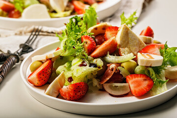 Close-up tasty salad with jamon, strawberries, grapes, mozzarella and olives with pomegranate sauce. Healthy and balanced nutrition. Organic food. Mediterranean cuisine recipes. Copy space