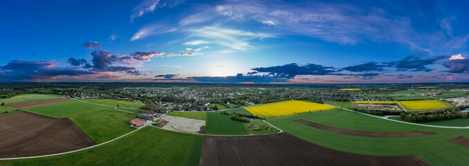 Agricultural view over growing fields and a idyllic placed village in the background, captured by a drone with copy space in southern bavaria, germany.
