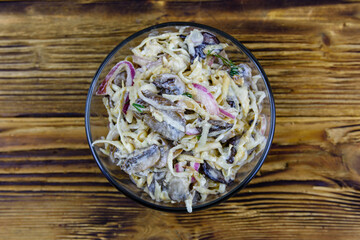 Salad with celery root, roasted mushrooms and onion stuffed with mayonnaise on a wooden table. Top view