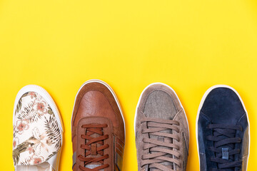 Pairs of male's and females's new sneakers on a yellow background. Flat lay. Copy space. Close up of shoes toes