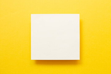 White memo pad on yellow background. top view, copy space