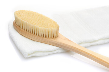 A dry massage brush made of natural materials and a cotton towel on a white background. Cleanliness and body care concept