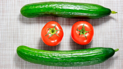 Whole cucumbers and tomatoes on a light surface. Ingredients for the salad.