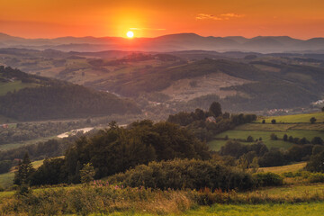Picturesque sunset in Beskid Sądecki seen from the tower in Wola Krogulecka, with views of the mountains and fields.
