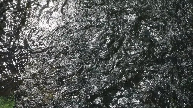 Water flow on a rough shallow river, top view. The waves sparkle in the sunlight, the power and energy of nature.