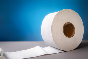 A roll of toilet paper on blue background close-up. The concept of panic purchasing of essential goods. Coronovirus, pandemic, hygiene. Copy space