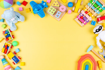 Colorful educational wooden plastic and fluffy toys for children on pastel yellow background. Top view, flat lay