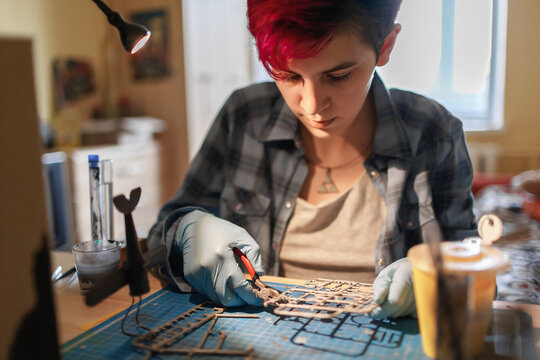 Geek teenage girl in protect eyeglasses engineering an airplane model at home, generation Z lifestyle, hobby and nerd subculture, authentic lifestyle character