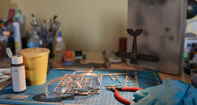 A workplace of geek teenage girl engineering an airplane model at home, generation Z lifestyle, hobby and nerd subculture, authentic lifestyle