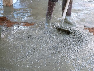 The plasterer is cleaning the cement floor to be smooth.