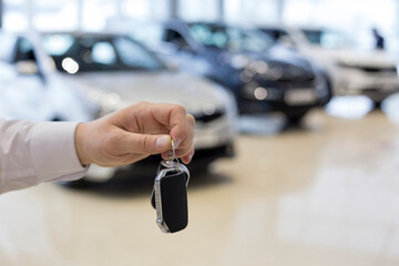 Salesman holding keys to a new car. Car auto dealership.
