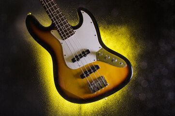 Korpus einer Bass Gitarre mit gelben Sprühnebel vor schwarzem Hintergrund IV