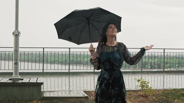 Woman hides under black umbrella enjoying rainy weather