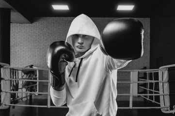 Brutal athlete boxing in the ring in a white hoodie covered with a hood. Mixed martial arts concept.