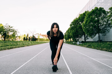 Fototapeta premium Young fitness girl doing stretching exercise outdoors on a sunny day. Fitness healthy lifestyle concept.