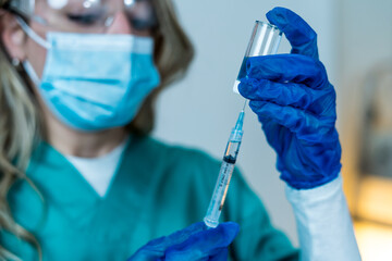 Female doctor or nurse holding COVID-19 Vaccine. Coronavirus medical treatment.