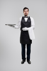 Smiling waiter with tray in studio
