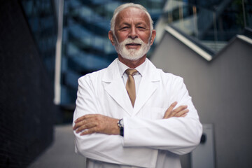 Fototapeta premium Doctor in white coat standing on street and looking at camera.