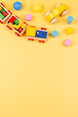 Baby kids toys. Wooden train, car, colorful blocks and balls on yellow background. Top view, flat lay