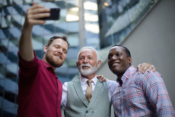  Three business men standing outside and using mobile phone. Focus is on background.