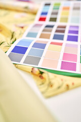 Tailor, atelier or seamstress concept. Textile colorful cloth samples palette catalogue and yellow fabrics lying on a table. High quality vertical photo