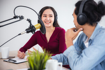 two Asian hosts radio recording podcast in broadcasting studio, Asian woman talking on microphone...