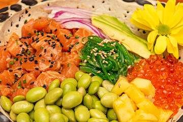 Closeup of ingredients used in salmon poke bowl with green beans, mango, red onion, seeds, seaweed