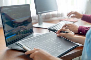 programmer writing program code with two monitors and working on a new software or hacker...