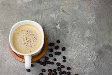 A Cup of hot Cappuccino coffee on wooden tray, with cofee beans on grey background. Selective focus, copy space.