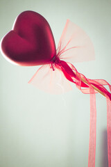 Red heart attached to a stick with a bow hanging