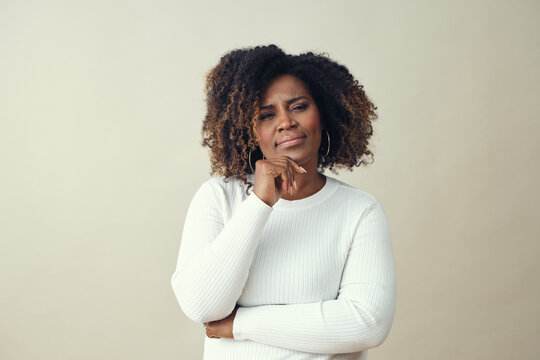 Thoughtful mid adult African American Black woman with hand in chin looking at camera against a white background