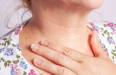 Vista del cuello de una mujer con una mano apoyada en el cuello