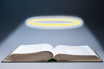 World Religion Day. An open book of the Holy Bible, with a glowing halo above it. Dark background. The concept of religion, faith, and spiritual education