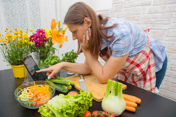 Woman In Kitchen Following Recipe On Digital Tablet