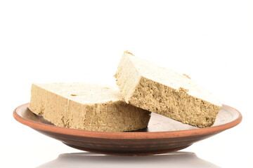 Two slices of vanilla halva on a clay plate, close-up, isolated on white.