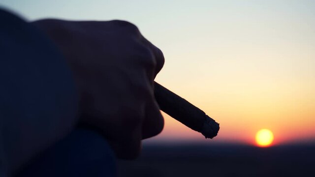 Smoking a cigar. Guy smoke cigar outdoors, spectacular sunset