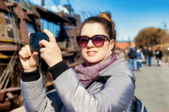 Portrait young tourist woman with phone, stands and takes photos of sights