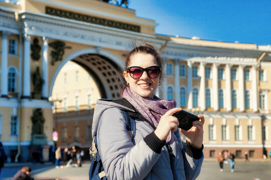 Portrait young tourist woman with phone, stands and takes photos of sights