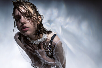 Model with wet hair in transparent dress and starfish earrings