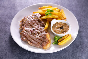 grilled beef steak with sauce and french fries
