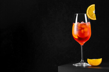 Aperol Spritz Cocktail in wine glass with ice and orange slice on dark background. Long fizzy drink