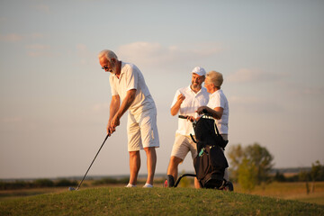 Three senior golfer on filed. Man playing golf. Focus is on man.  His support is always there.