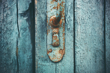 An old blue-painted closed wooden front door with a rusty handle and keyhole. Secret.