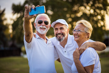 Senior golfers using phone and taking self portrait.  Time for memories.