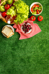 Summer picnic setting. Basket with food on red cloth, top view