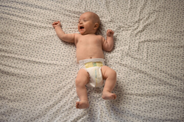 Adorable cute baby lying on his back on the bed