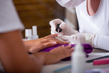 Woman hands in a beauty salon getting nails polished - obrazy, fototapety, plakaty