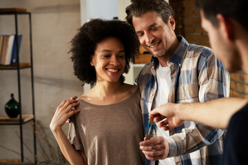 Smiling couple is taking keys from their new apartment. Husband and wife are moving into the apartment..