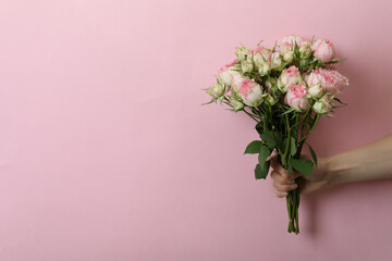 Female hand hold roses on pink background