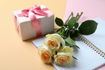 Roses, gift box and copybook on two tone background